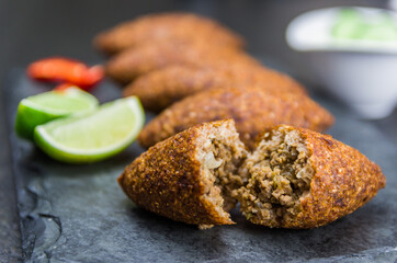 Delicious Lebanese  food, kibbeh (kibe) on black slate stone and granite background.