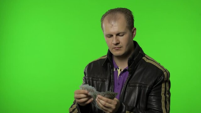 Man employee in jacket counts dollar cash banknotes and puts money to his pocket. Money cash income