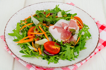 Plate with fresh salad leaves, parmesan slices and jamon. Studio Photo