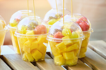 Plastic cup with fruits like pineapple and blackberries on the counter
