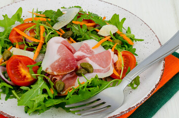 Plate with fresh salad leaves, parmesan slices and jamon. Studio Photo