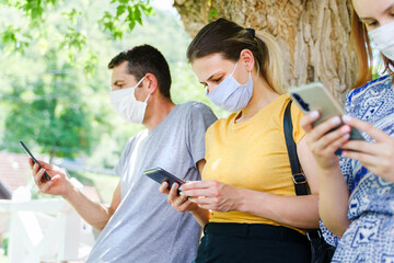 Side view of caucasian man and women use mobile phones - Modern communication online texting social network message - Group of people with mask hold mobile phones - social distance new normal concept