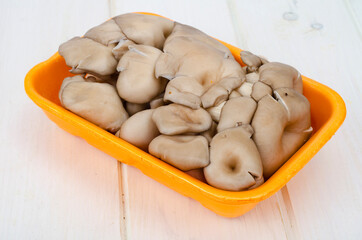 Fresh oyster mushrooms in packaging on wooden background