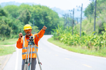 Engineer working with theodolite transit equipment and command radio communication at road...