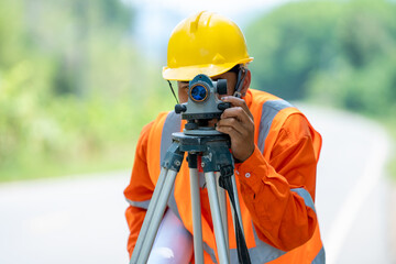 Engineer working with theodolite transit equipment at road.