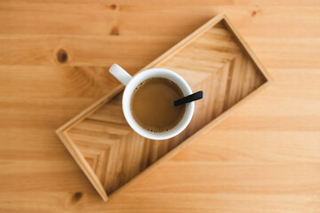 oat milk latte mug from top down perspective on bamboo tray on matching wooden table