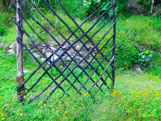 sculpture of logs in grass area with stone wall in the background
