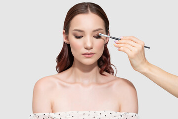 Fototapeta premium Artist Applying Cosmetic On Eyelid Of Caucasian Model