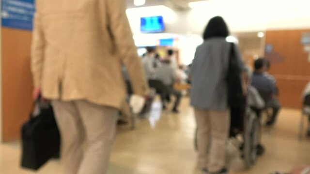マスクを付けた患者で混み合う病院のロビー  ぼかし背景素材 ソーシャルディスタンス 新しい生活様式 4K / Blurred shot of patients with mask waiting in the crowded lobby at hospital in Japan. Social distancing. 4K