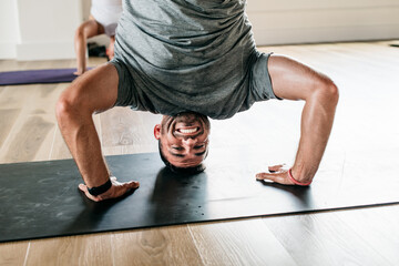 Man doing yoga headstand while smiling