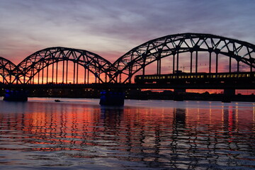 Fototapeta na wymiar Cityscape of a glowing sky and the Daugava River Railway Bridge in Riga Latvia