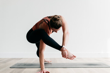 Fototapeta na wymiar Woman doing yoga in yoga studio against a white background