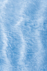 Blue sky and thin striped white cloud layer as a nature background
