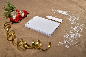The toy pickup truck carries a bag of gifts, a Christmas tree and blank notebook with a white crayon next to it snow,