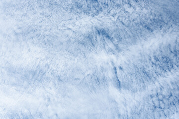 Blue sky and thin striped white cloud layer as a nature background
