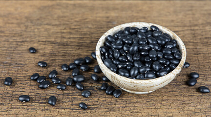 Fototapeta na wymiar Raw black beans in wooden bowl on wooden table background.
