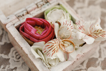 Obraz na płótnie Canvas Close up view of white flowers and pink lotus, wedding rings in rustic wooden box with plants inside