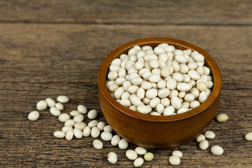 Raw white beans seed in wooden bowl on wooden table background.