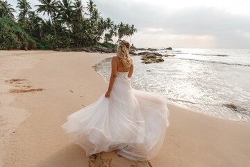 Fototapeta na wymiar Bride walking along sea coast wearing beautiful wedding dress, dance on sandy beach, tropical island