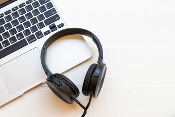 computer notebook with black headphone of listening of lifestyle on background white wooden