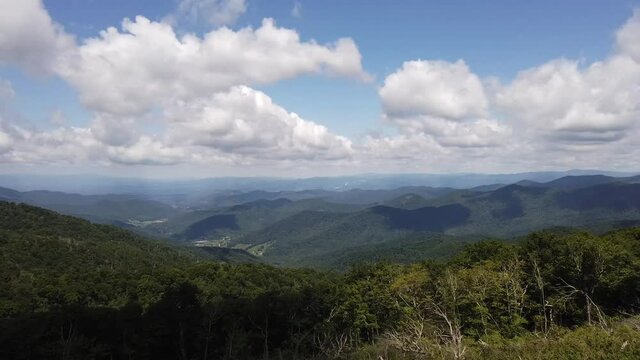 Time lapse: beautiful majestic long-range views of blue ridge North Carolina mountain ranges and horizon with white puffy cumulus and stratus clouds billowing, mushrooming and moving in blue sky