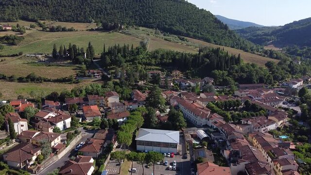 Ascending aerial overview of Molin del Piano, ancient town near Arno river valley. South Florence area near Pontassieve, Tuscany Italy. Mid summer cloudy day at sunset