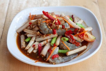 Lotus stem salad and shrimps is food of Thai style local the eastern in white plate on the wooden table.