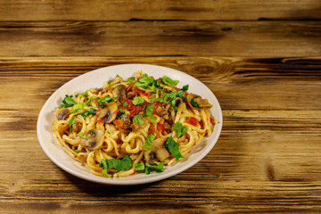 Pasta with mushrooms and tomato sauce on wooden table