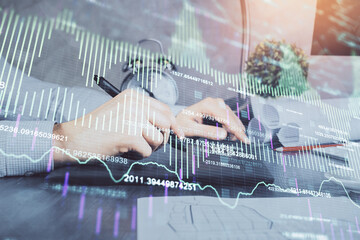 Double exposure of man's hands holding and using a phone and financial graph drawing. Analysis concept.