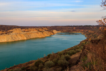Fototapeta na wymiar View of a lake with sandy shores in flooded sand quarry