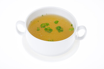 Transparent meat broth with herbs in white plate