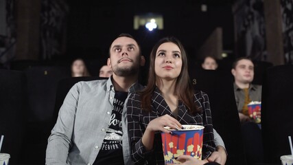 Love couple watching movie and eating popcorn in cinema theatre. Movie entertainment