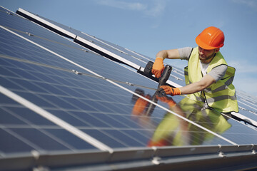 Male worker with solar batteries. Man in a protective helmet. Installing stand-alone solar panel...