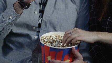 Obraz premium Loving couple are eating popcorn in cinema and watching the movie.