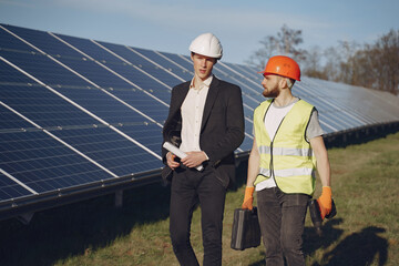 Businessman and worker near solar energy batteries. Business client showing photovoltaic detail to foreman. Two men making deal. © prostooleh