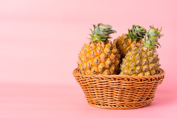Fresh pineapple fruit in a basket on pastel pink background, Tropical fruit