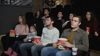 People are eating popcorn and watching a movie in the cinema