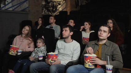 People are eating popcorn and watching a movie in the cinema
