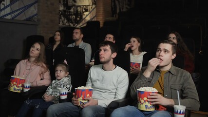 People are eating popcorn and watching a movie in the cinema