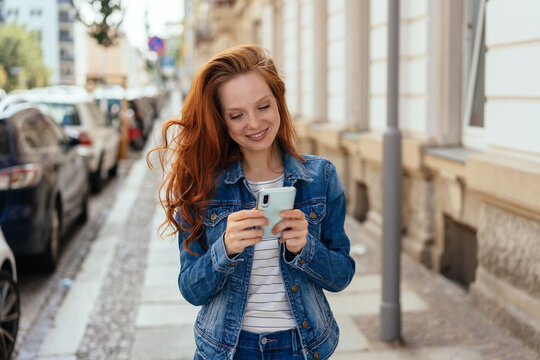 Young redhead woman reading on her mobile