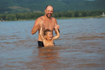Happy family concept. Father playing with son in the water 