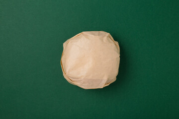 Packed burger on green background, top view. Wrapped hamburger sandwich, blank mock up.