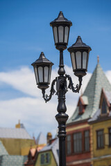 Fototapeta na wymiar Street lamppost against the old buildings background. Classic victorian street lamps on an old fashioned iron lamp post set