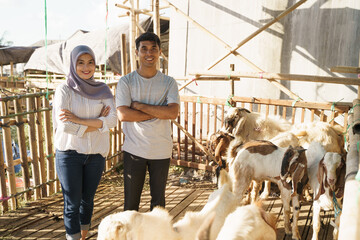 happy man and woman standing in the farm. eid adha sacrifice concept