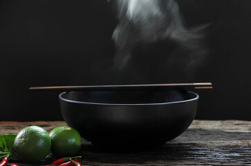 Bowl of hot soup with steaming on wooden table on black background selective focus. hot food concept.