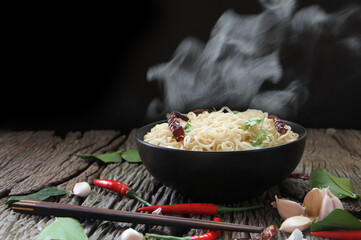 Noodles with steam and smoke in bowl on wooden. Hot food concept. Asian style of food.