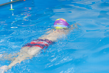 the child learns to swim in the pool, view from the back