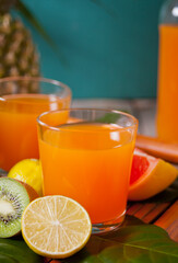 Glasses of tropical exotic multifruit juice under a palm leaves.