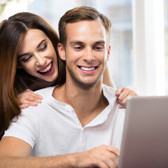 Image of happy excited smiling couple using laptop at home. Internet, shopping, online store, love, relationship concept - man and woman with computer. Square composition picture.