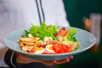 Healthy Green Organic Caesar Salad with Cheese and Croutons. Waiter in white uniform, shirt, serving caesar salad.